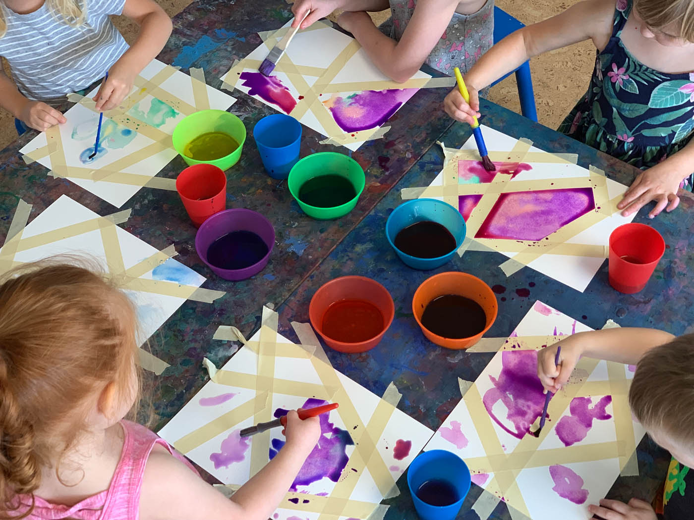 Kids Garden employee working with kids on paper crafts.