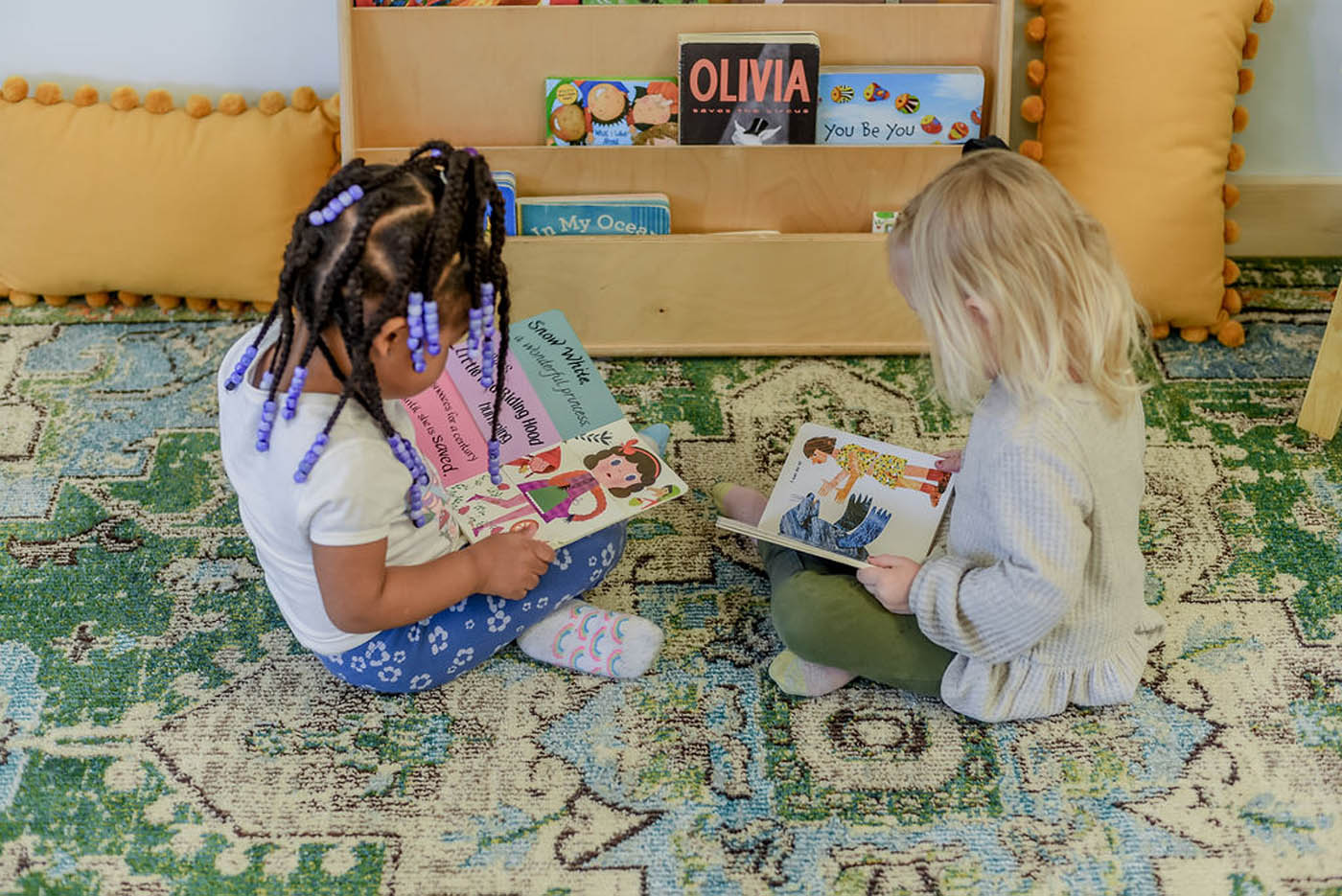 Kids at Kids Garden reading books on a green rug.