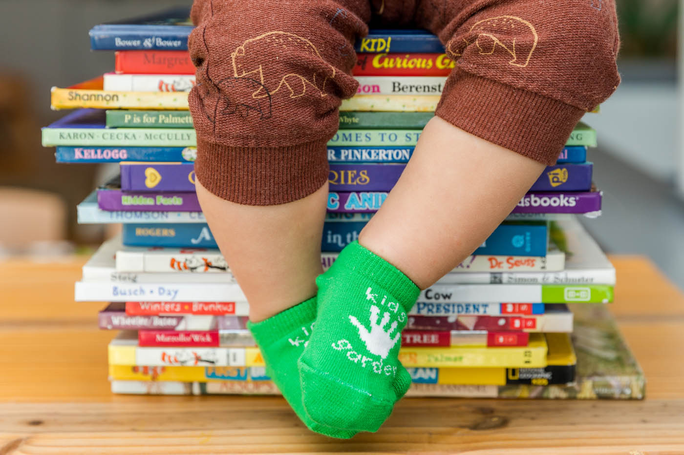 A little kid at Kids Garden sitting on our learning center books.