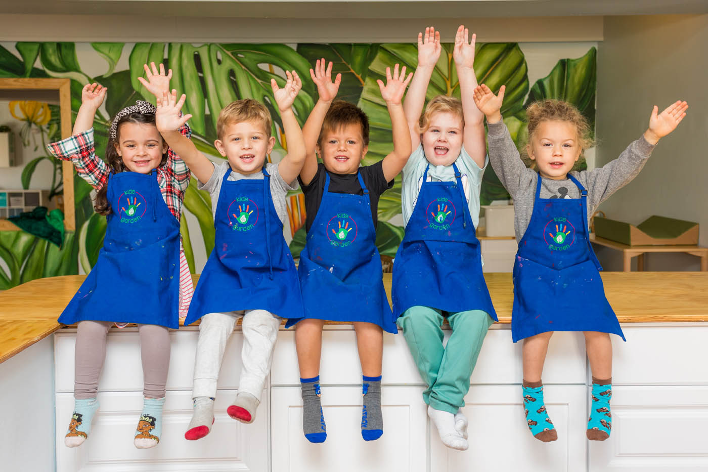 Kids in blue aprons at Kids Garden Houston learning center.